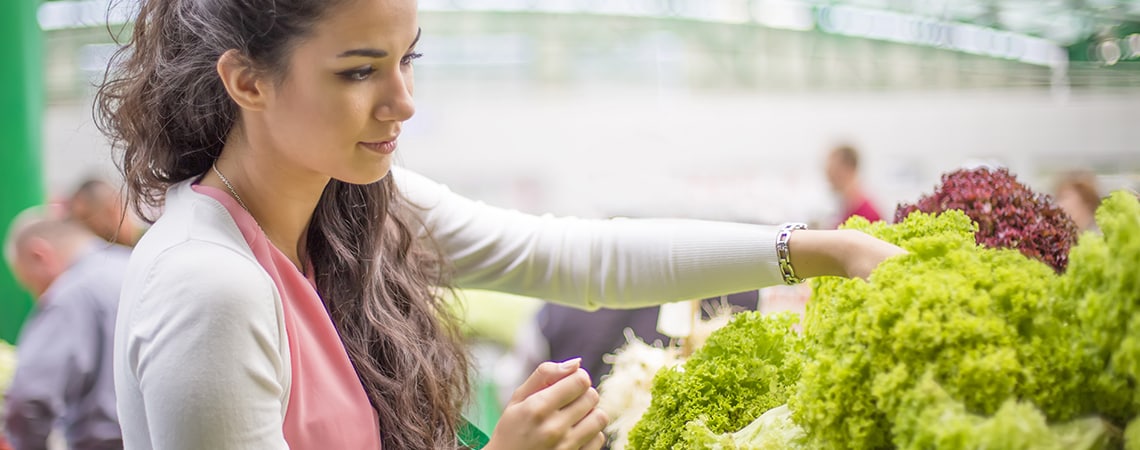 Mlada žena bira među raznim vrstama salata dok kupuje namirnice.